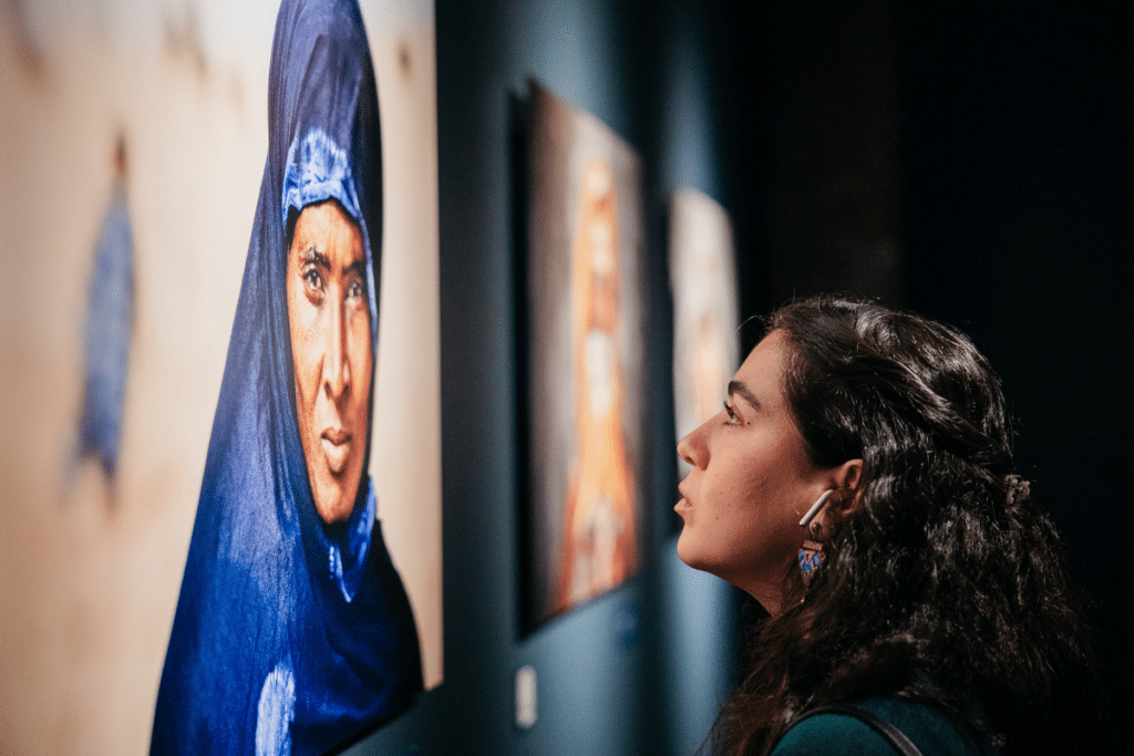 Young woman looking at a picture at the Steve McCurry. ICONS: An Extraordinary Photography Exhibition