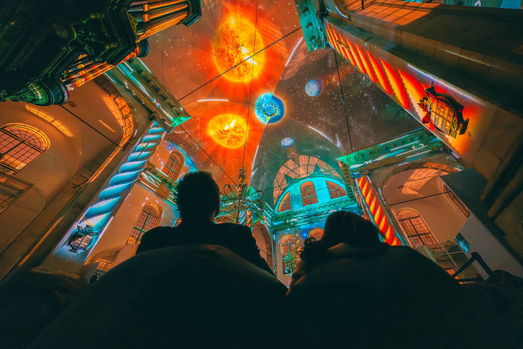 The inner walls and ceiling of a building are lit up with a projection of the solar system as part of Eonarium Genesis.