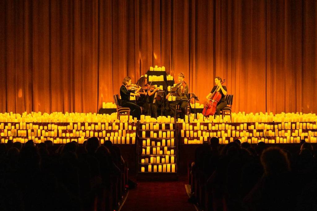 A string quarter performing on the candlelit stage of Koninklijk Theater Tuschinski during a Candlelight concert