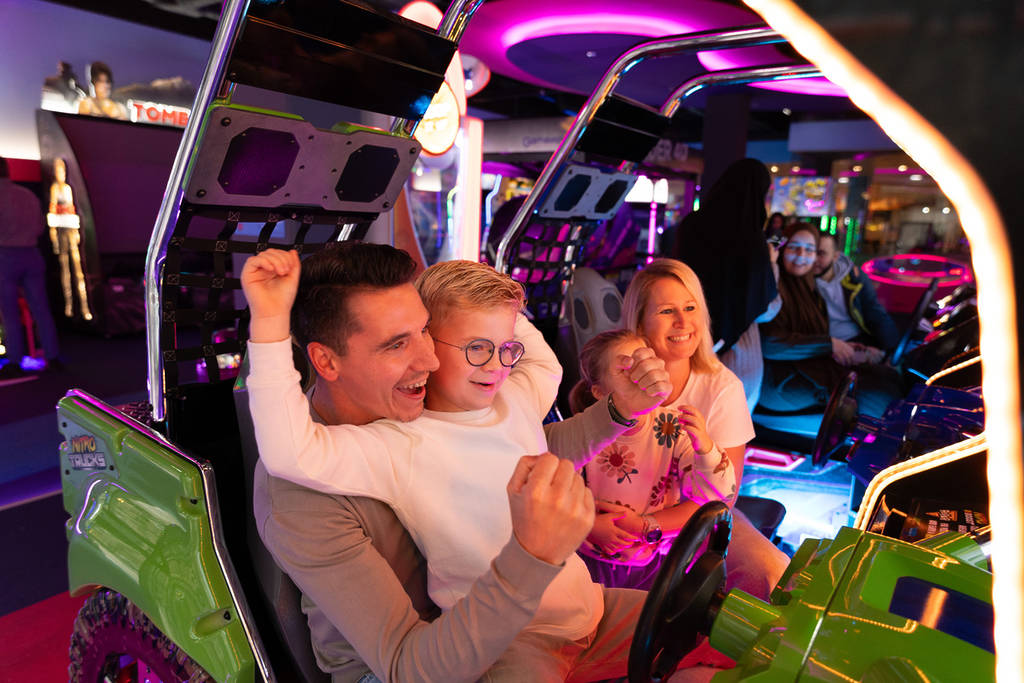 Family plays racing game together at the arcade