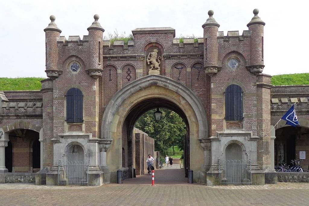 Il monumentale portone d’ingresso in mattoni della fortezza di Naarden del 1877, decorato con un rilievo del Leone olandese e affiancato da piccole torrette.