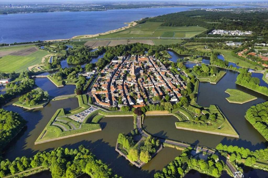 Ampia foto aerea dell'iconica stella a sei punte della fortezza di Naarden, che mostra l'intera struttura geometrica delle fortificazioni militari e dei canali circostanti.