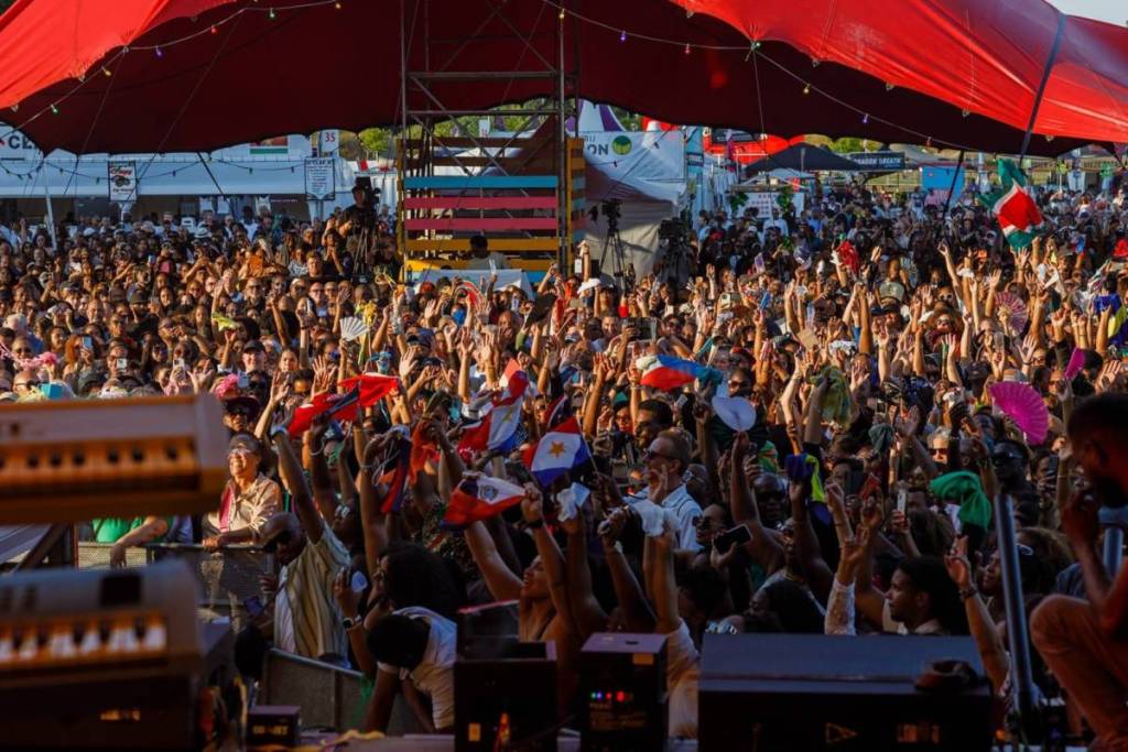 An impressive view from the stage of a massive, densely packed crowd beneath a large, bright-red festival tent.