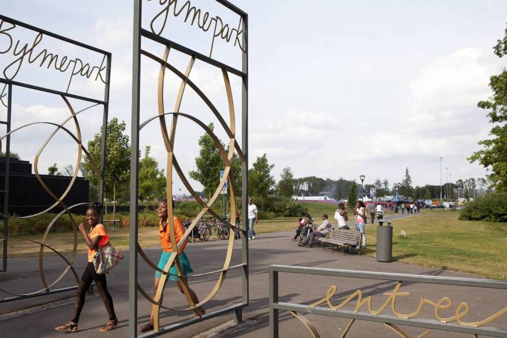 Zwei lächelnde junge Frauen gehen durch die großen, eleganten Metalltore des Nelson-Mandela-Parks