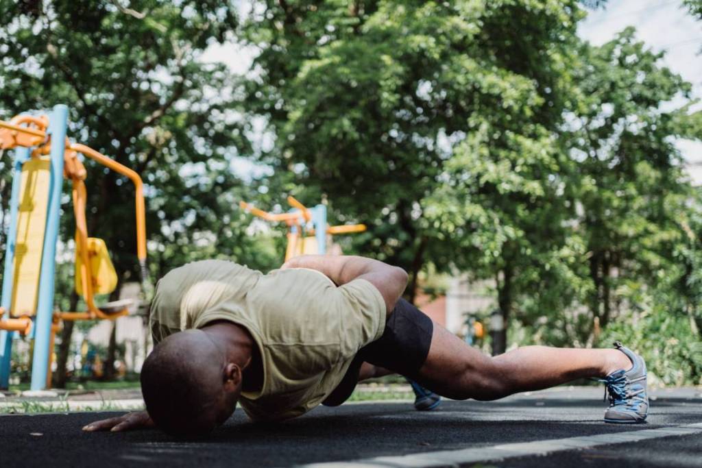Een man voert een zware push-up uit op de grond van een gratis outdoor fitnesspark.