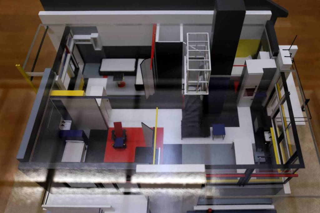 Bovenaanzicht van een gedetailleerde maquette van het Rietveld Schröderhuis, die de open en flexibele indeling van het interieur toont met geometrische vormen en De Stijl-kleuren.