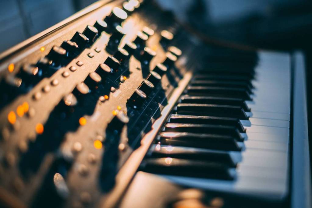 A close-up of an electronic synthesizer with illuminated buttons and black-and-white piano keys for live music and concerts in Amsterdam