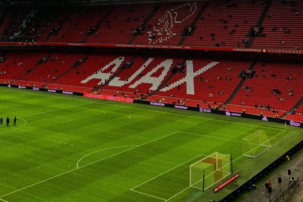 View of the red stands at the Johan Cruijff ArenA in Amsterdam, where the club name “AJAX” is formed with white seats along the green soccer field