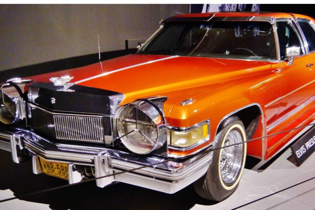 Der auffällige, leuchtend orangefarbene Cadillac Fleetwood von Elvis Presley aus dem Jahr 1976, mit glänzendem Chrom und einem personalisierten Nummernschild, ausgestellt im Louwman-Museum.