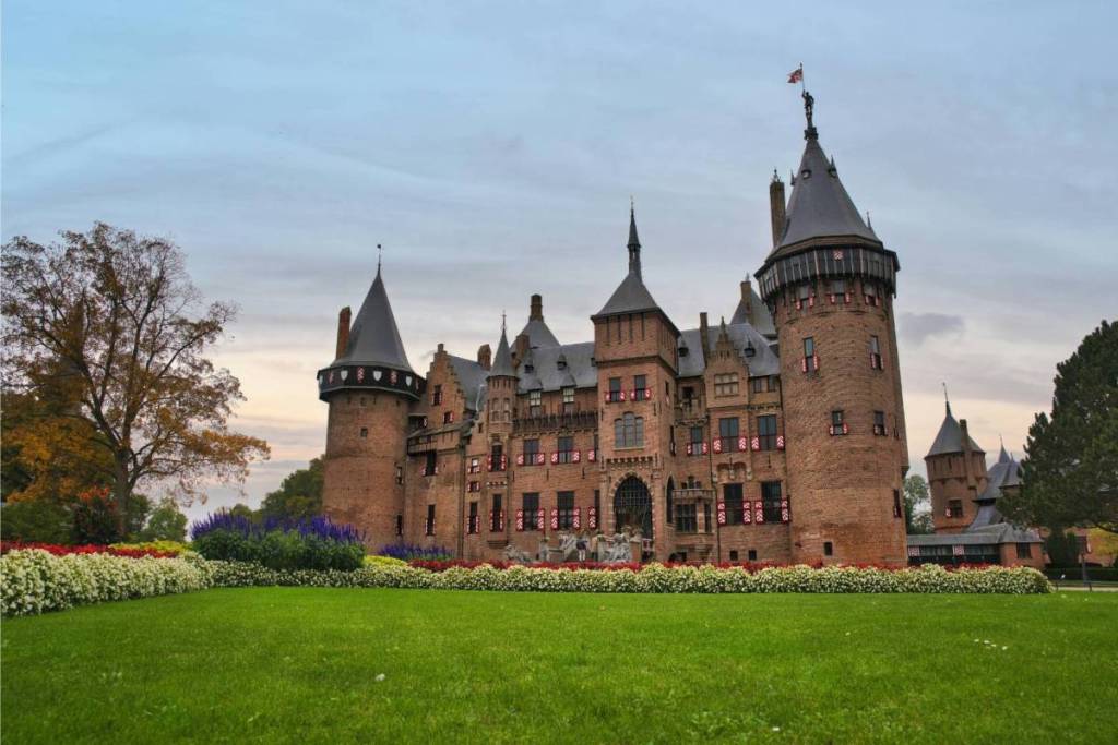 Vista frontal del castillo de Haar, en Utrecht, con exuberantes parterres y un césped bien cuidado bajo un cielo nublado.
