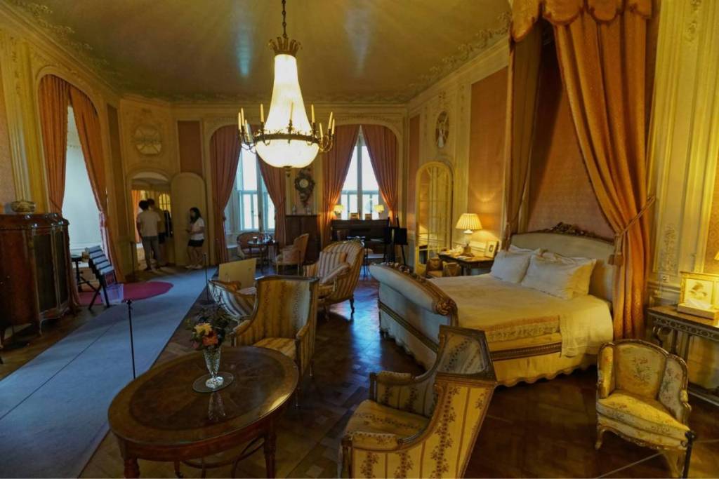 El suntuoso interior histórico de un lujoso dormitorio en el castillo de Haar, con una cama con dosel antigua, cortinas doradas y una gran lámpara de araña de cristal.