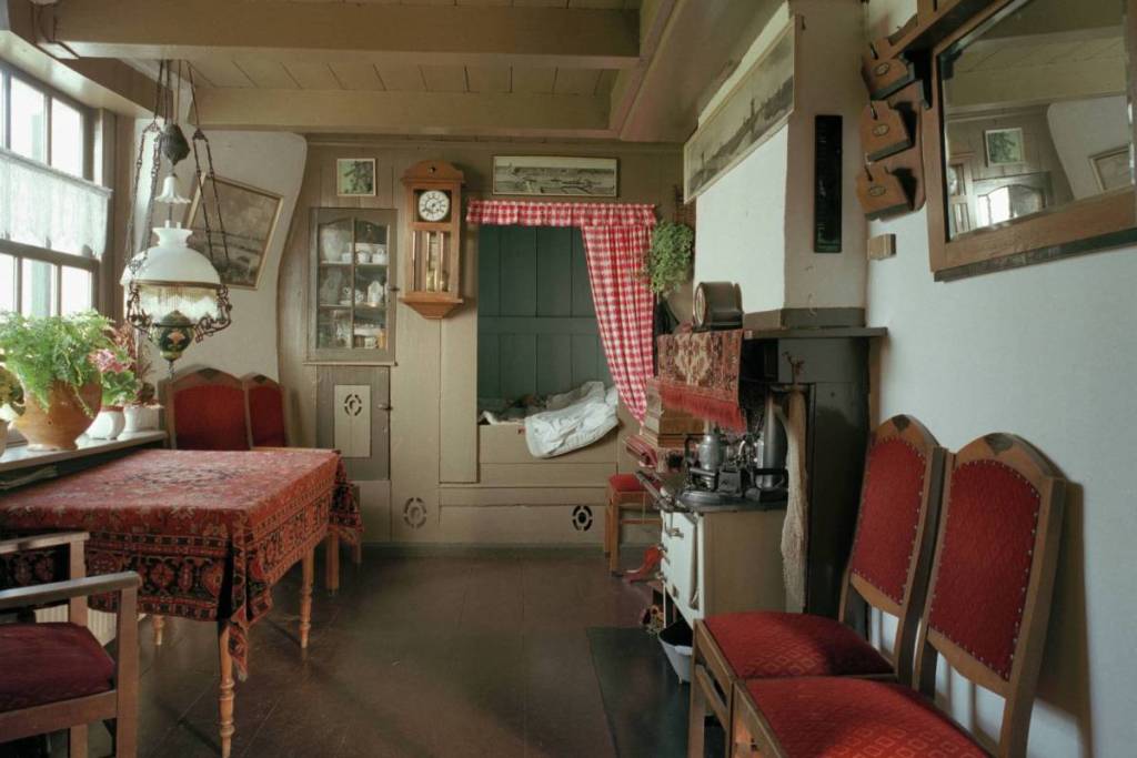 The authentic Old Dutch interior of a polder mill in Kinderdijk, furnished with a traditional box bed and nostalgic furniture.