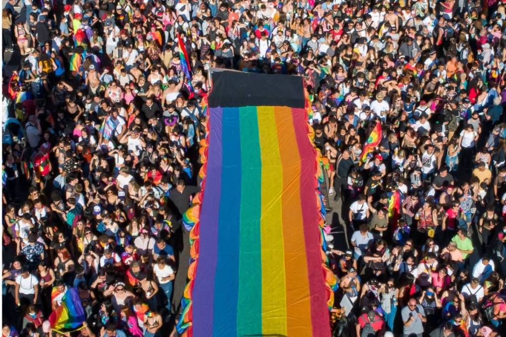 Vista aérea de una gran multitud que lleva una enorme bandera arcoíris por la calle durante la Marcha del WorldPride.