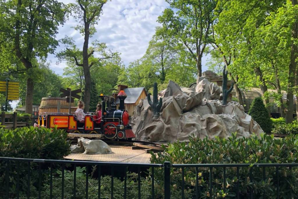 Kinderen in het overdekte Locomotion-stoomtreintje dat langs een decor van rotsen en cactussen rijdt in attractiepark Duinrell.