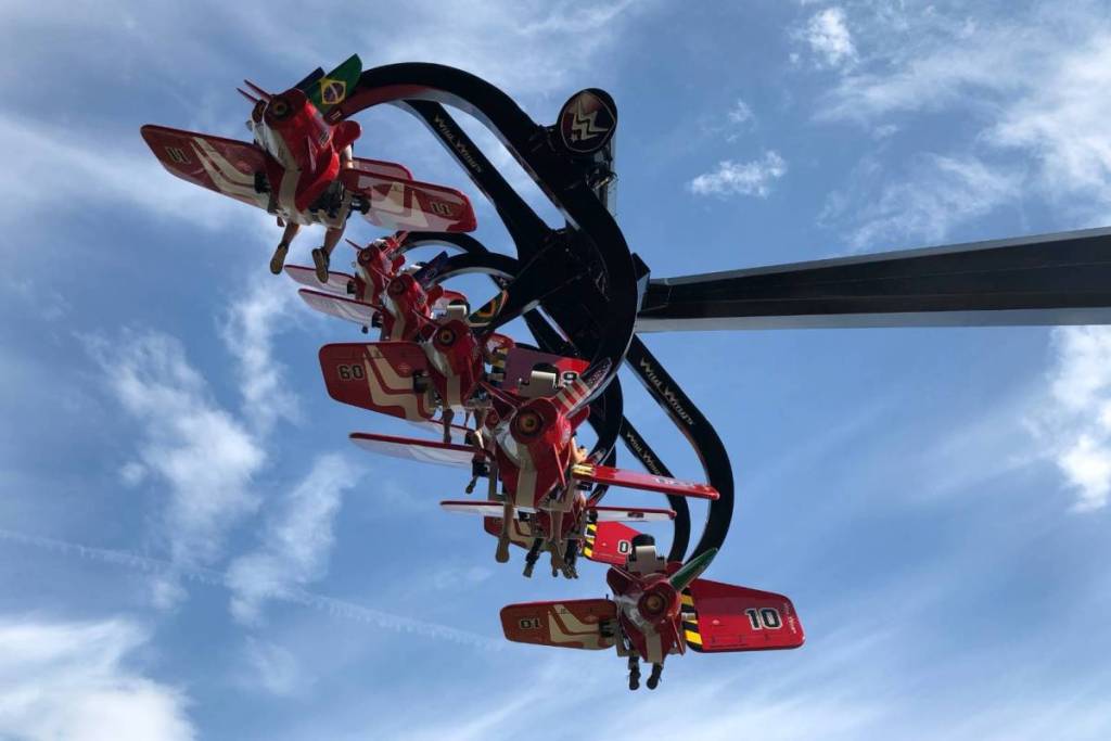 De rode vliegtuigjes van de thrillride Wild Wings die over de kop draaien tegen een helderblauwe lucht in Duinrell.