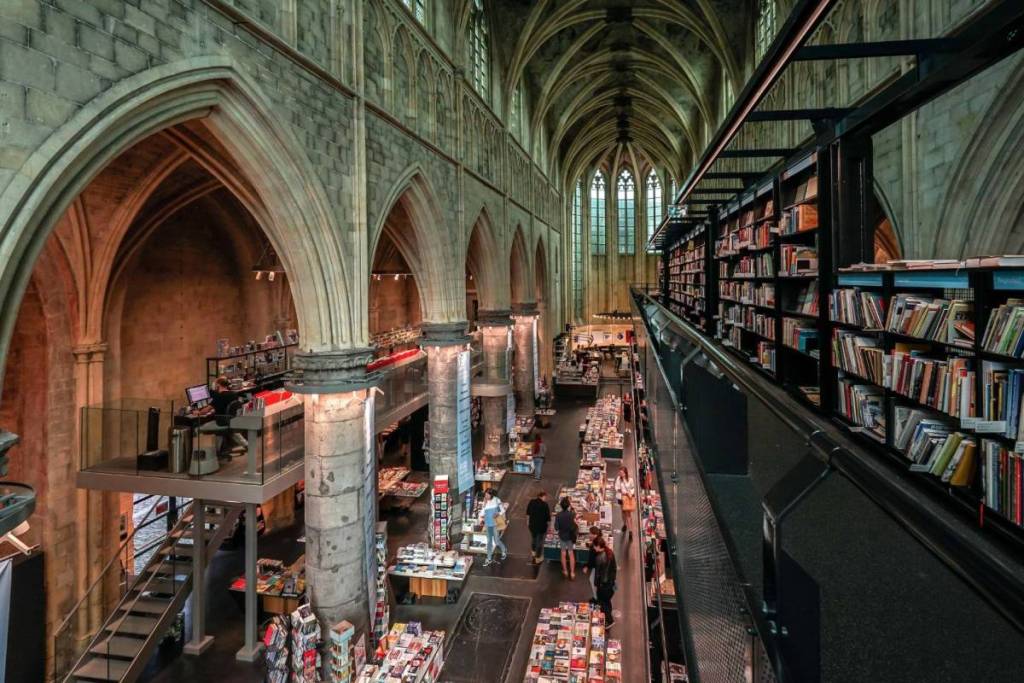 View of the impressive nave of Boekhandel Dominicanen, featuring the three-story-high book tower and medieval stone arches.