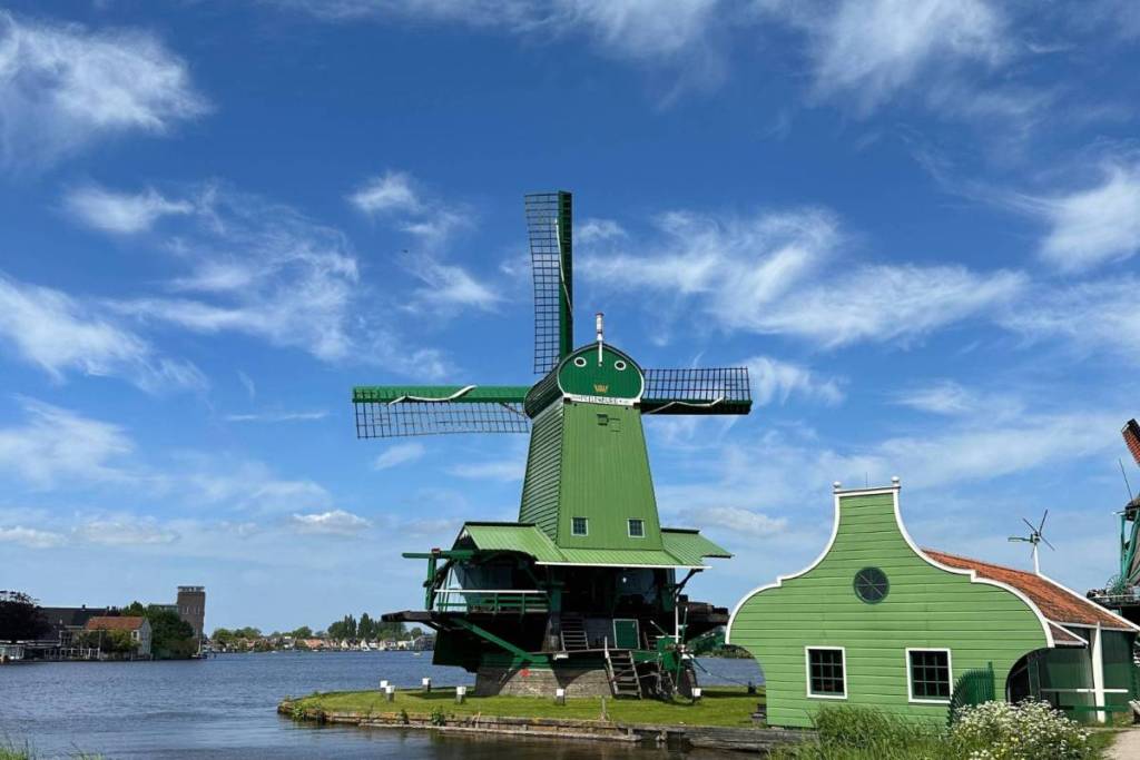 Il caratteristico mulino verde in legno «Het Jonge Schaap» sulle rive dello Zaan, allo Zaanse Schans, sotto un cielo azzurro e limpido.