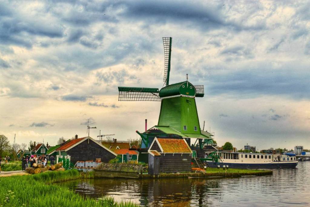 Storico mulino verde dei polder con fienili tradizionali in legno e cataste di legna sulle rive dello Zaan.