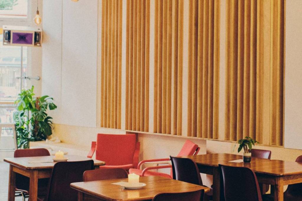 Interior del café musical dubble, con paneles acústicos de madera en las paredes y cálidas mesas de madera