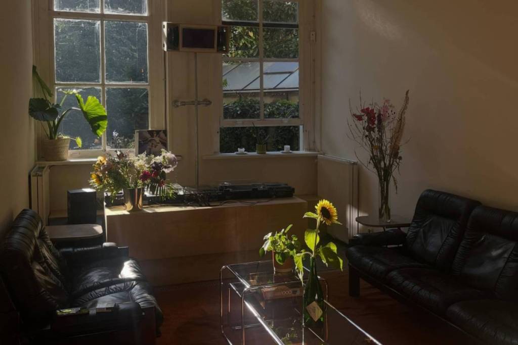 Zona de descanso con sofás de cuero negro y una cabina de DJ de vinilo con altavoces personalizados en dubble