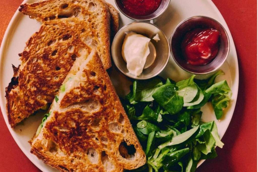 Un sándwich tostado con ensalada fresca y salsas en un plato en el café musical dubble de Ámsterdam