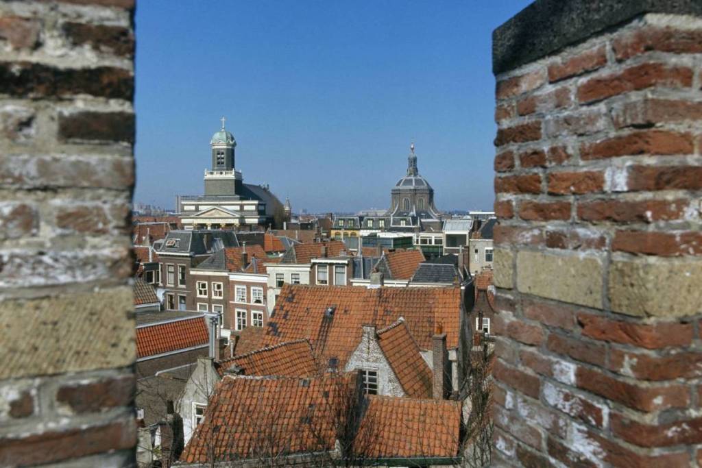 Vista de los tejados rojos y las históricas torres de las iglesias de Leiden desde el pasadizo entre las almenas del castillo.