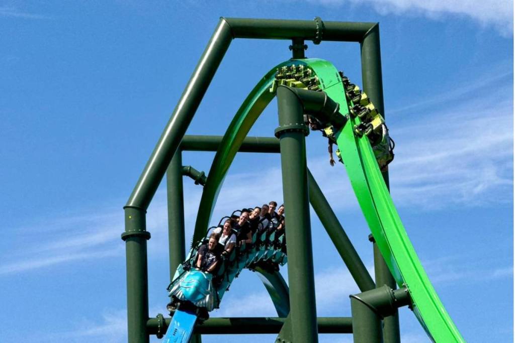 Besucher im blauen Zug der rasanten Stahlachterbahn Goliath vor blauem Himmel in Walibi Holland.