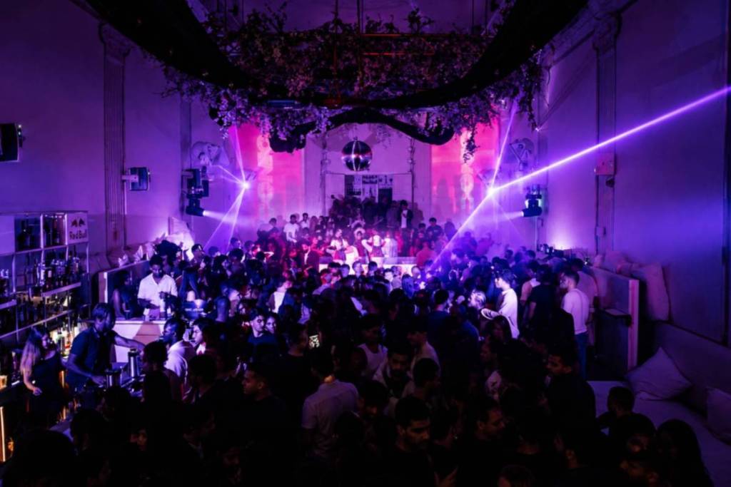 Pista de baile abarrotada en el Supper Club de Ámsterdam, iluminada por rayos láser morados.