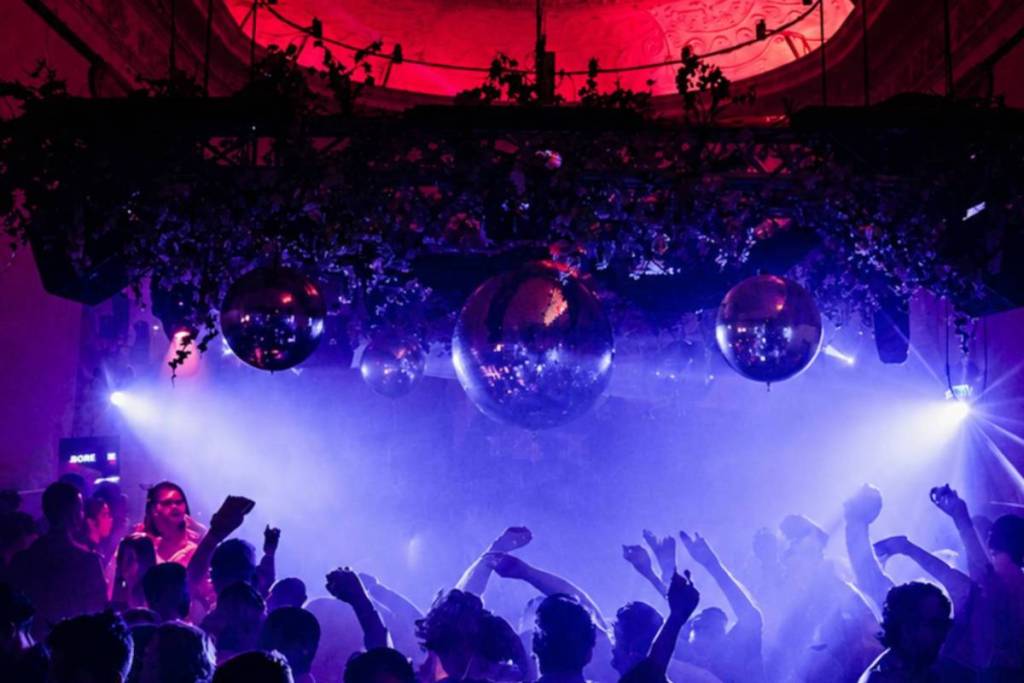 Fiesteros con las manos en alto bajo enormes bolas de discoteca en la pista de baile del Supper Club.
