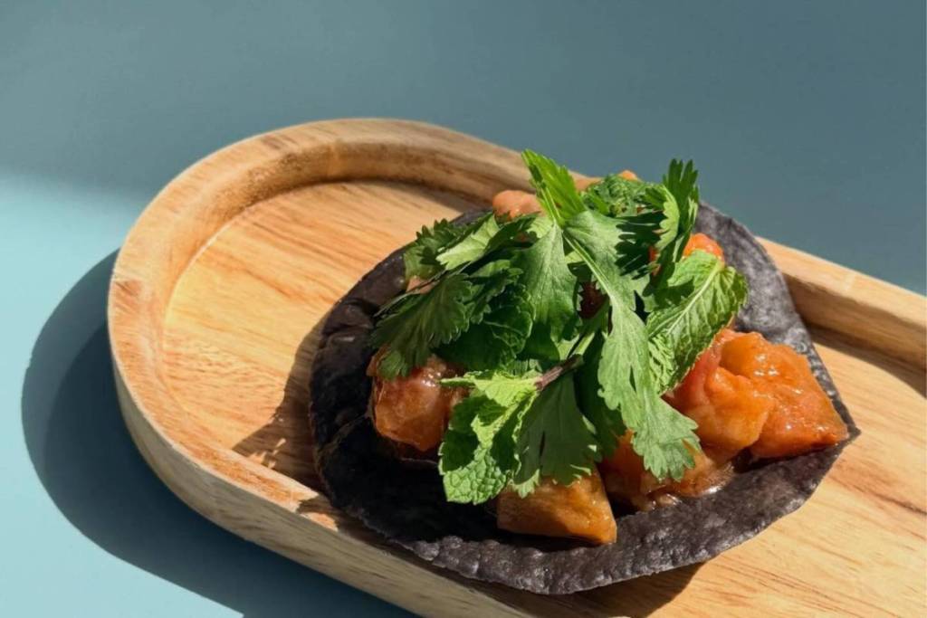 An authentic blue corn tortilla taco with layered toppings and fresh herbs at a Mexican restaurant in Amsterdam.