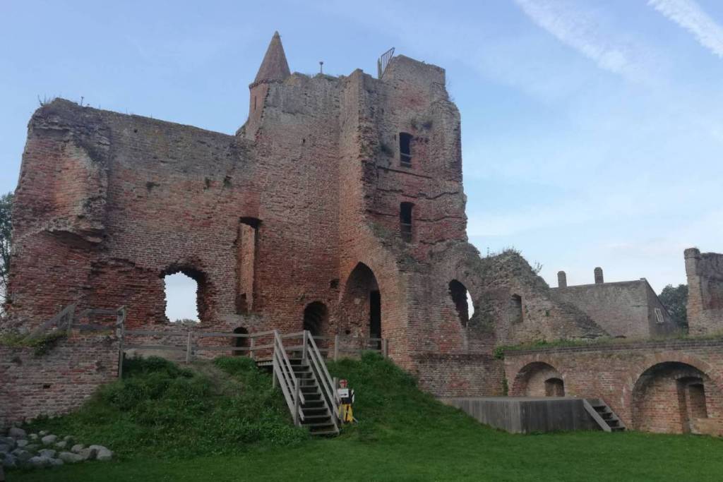 Vista dal basso all’interno del cortile del Castello di Brederode, con le alte mura di pietra fatiscenti, i passaggi ad arco e le scale di legno.