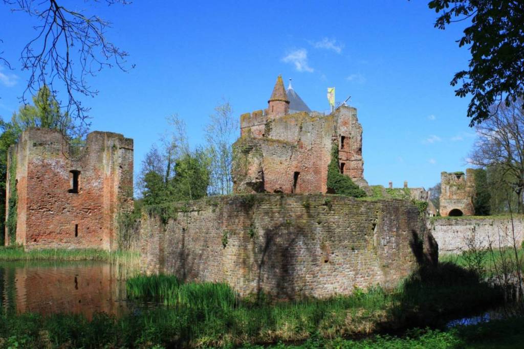 Di giorno si gode di una vista chiara sulle rovine del castello di Brederode, con la torre di mattoni rossi, le mura esterne e il riflesso nell’acqua circostante.