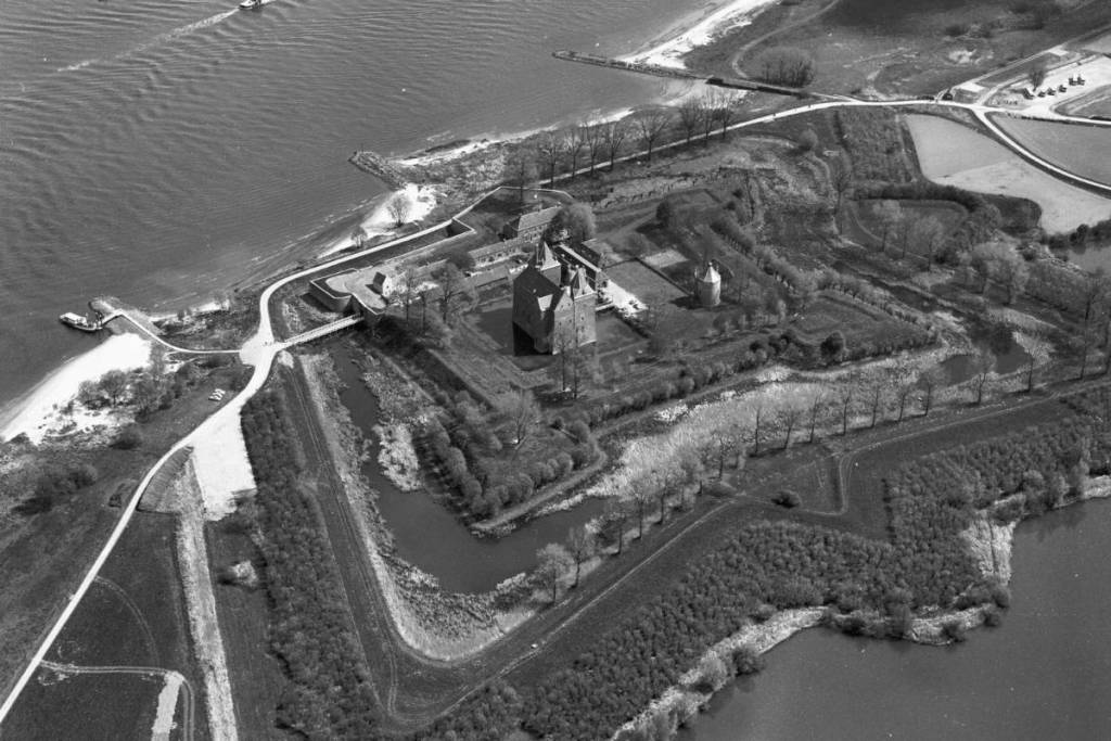 Foto aérea en blanco y negro del castillo de Loevestein, con vistas al castillo, las fortificaciones circundantes en forma de estrella, los canales y el río contiguo.