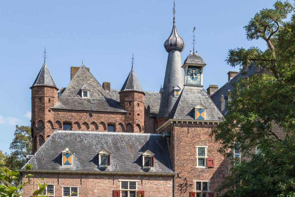 La fachada y las torres del castillo medieval de Doorwerth, a orillas del Rin, en Gelderland, bajo un cielo azul claro.