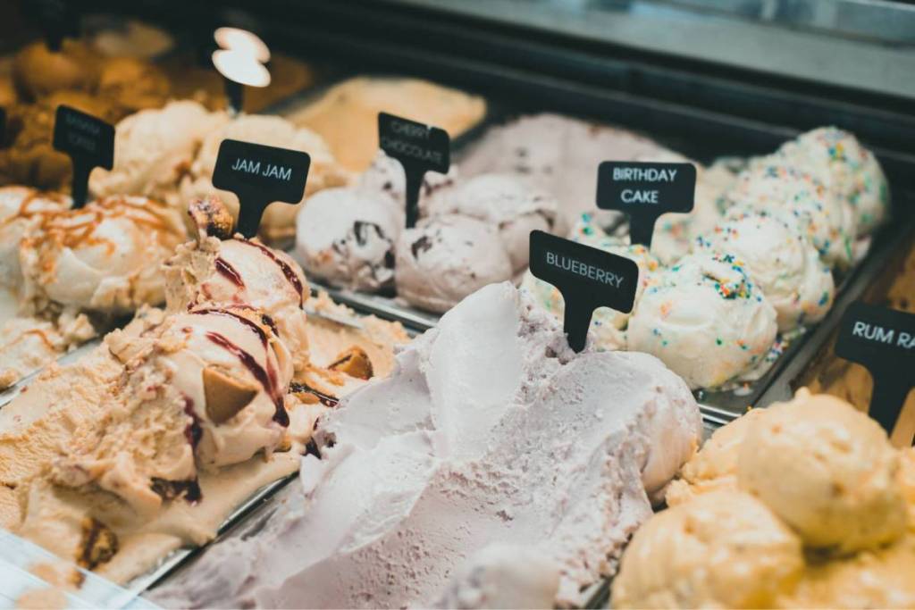 La vitrina de una heladería artesanal con varias bolas de helado italiano y sabores como arándanos, mermelada y tarta de cumpleaños.