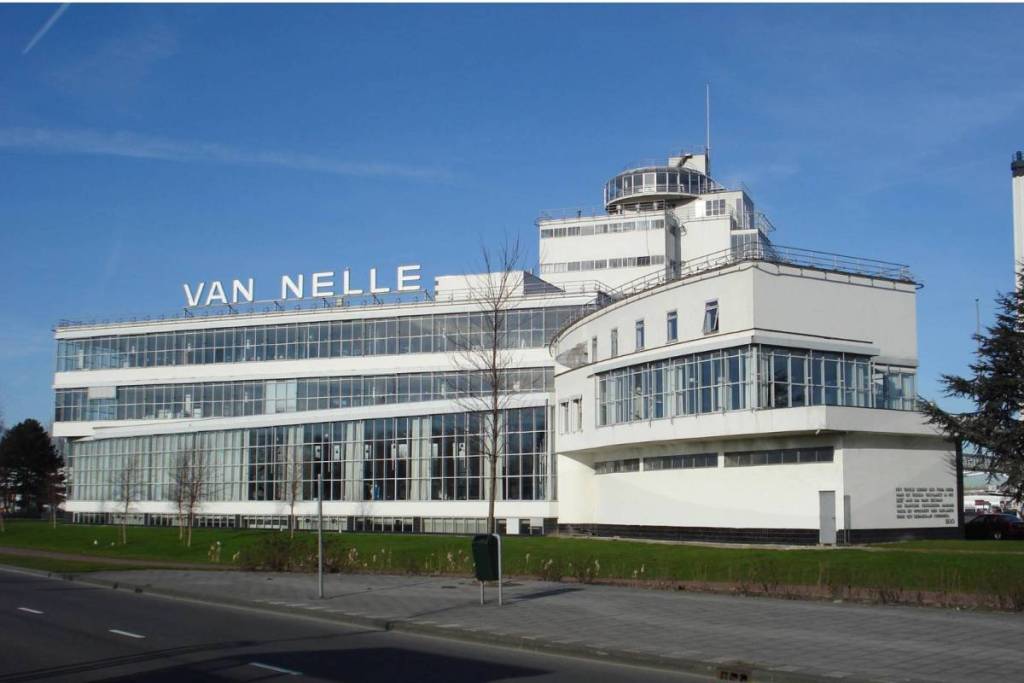 Exterior del moderno edificio principal de la fábrica Van Nelle, con grandes fachadas acristaladas.