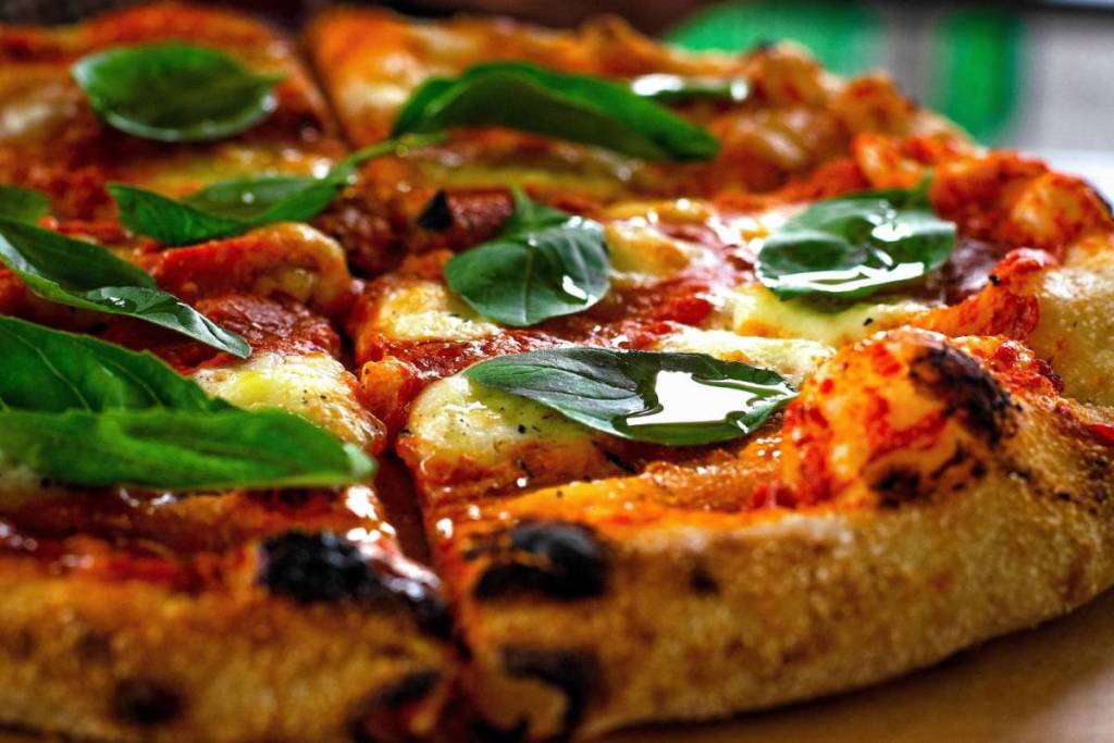 Close-up van een pizzapunt met gesmolten mozzarella, tomatensaus en een luchtige, knapperige korst.