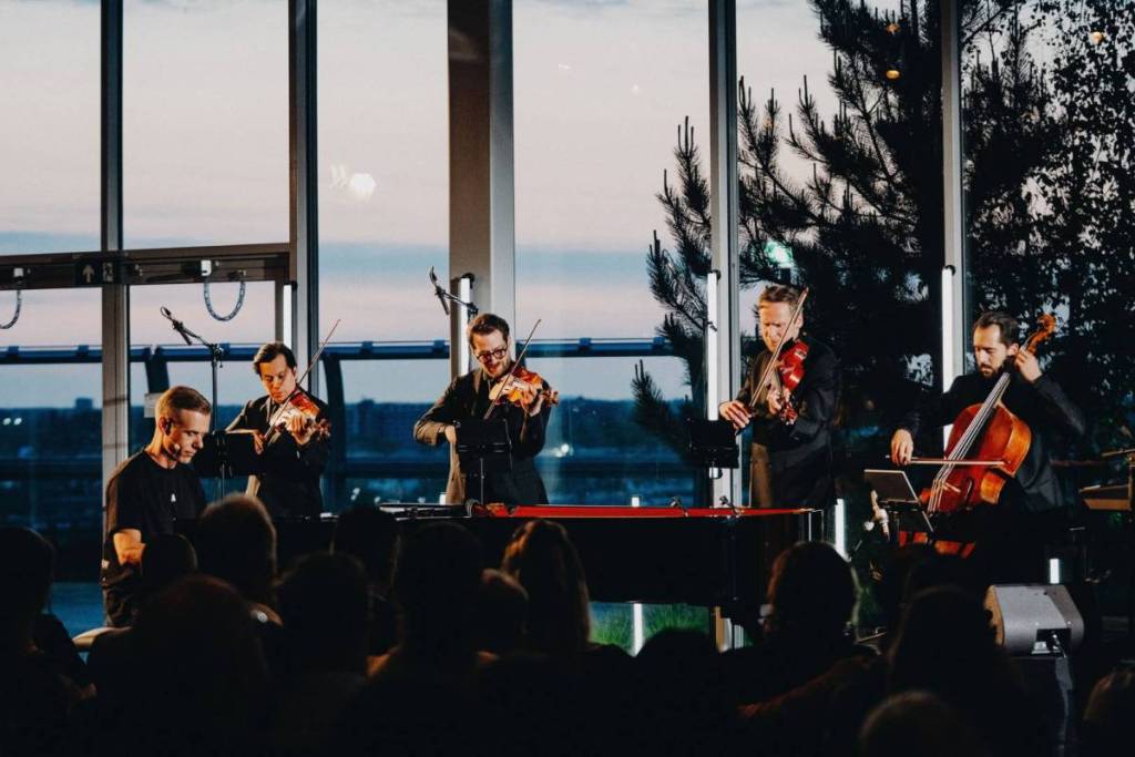 Armin van Buuren tocará el piano en el escenario, acompañado por cuatro instrumentistas de cuerda del Cuarteto Hydra, frente a un gran ventanal con vistas a la puesta de sol.