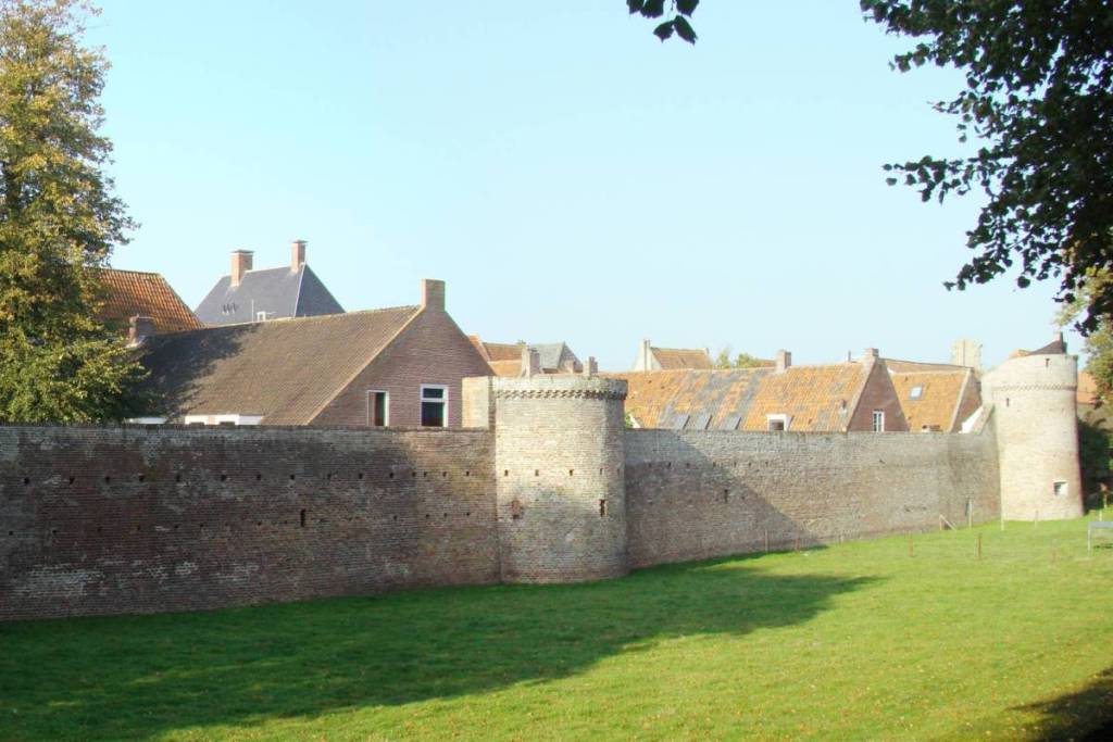 Vue sur les remparts historiques et le talus de défense d’Elburg, avec le double fossé au premier plan.