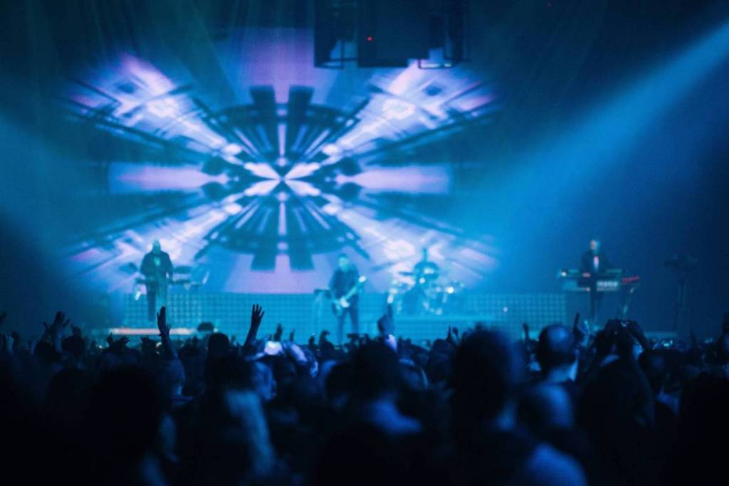 Liveconcert met blauwe lichtshow in een Amsterdamse poptempel.