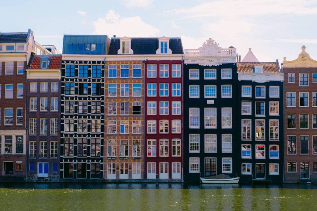 Een opvallende rij met karakteristieke, gekleurde grachtenpanden langs het water in het centrum van Amsterdam.