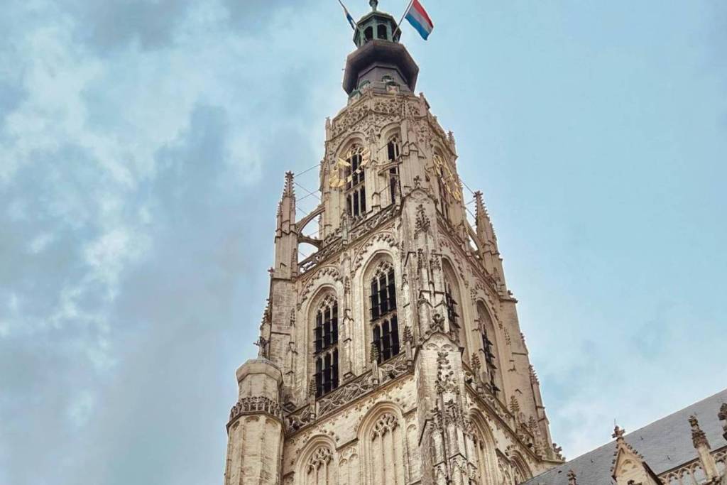 La torre de 97 metros de altura de la Grote Kerk de Breda, con su suntuosa decoración, recortada contra un cielo nublado.