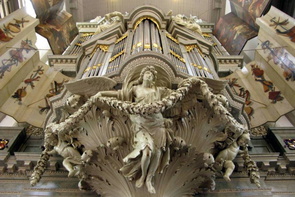 El órgano principal de la Westerkerk, fotografiado desde abajo, ricamente decorado con un ángel de mármol, guirnaldas y contraventanas pintadas.
