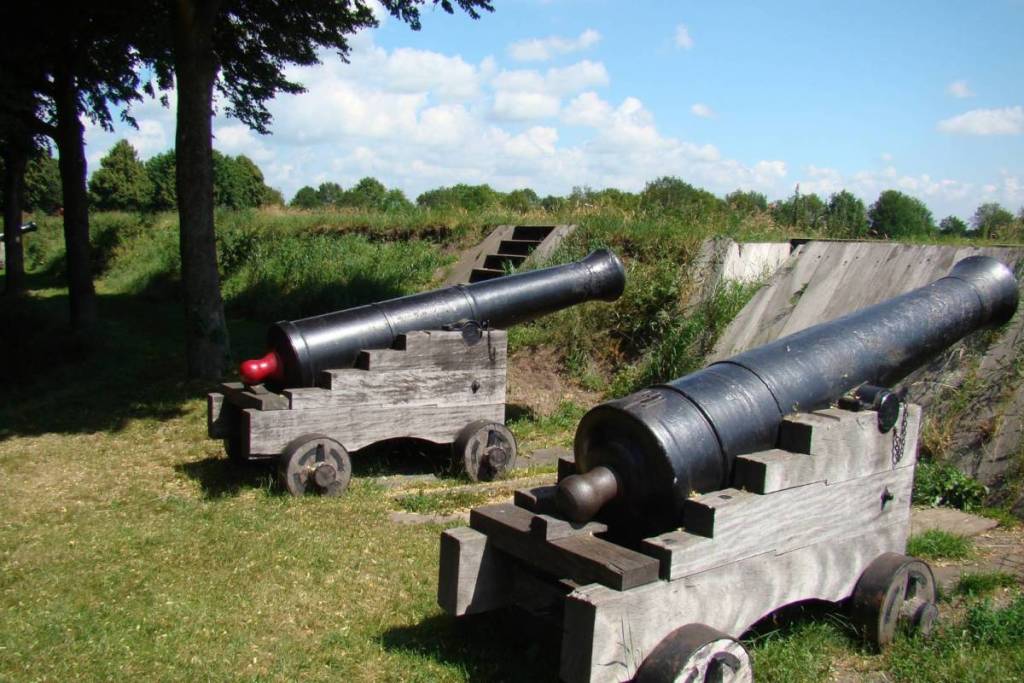 Deux canons noirs historiques montés sur des affûts en bois sur les remparts verdoyants de la forteresse de Bourtange.