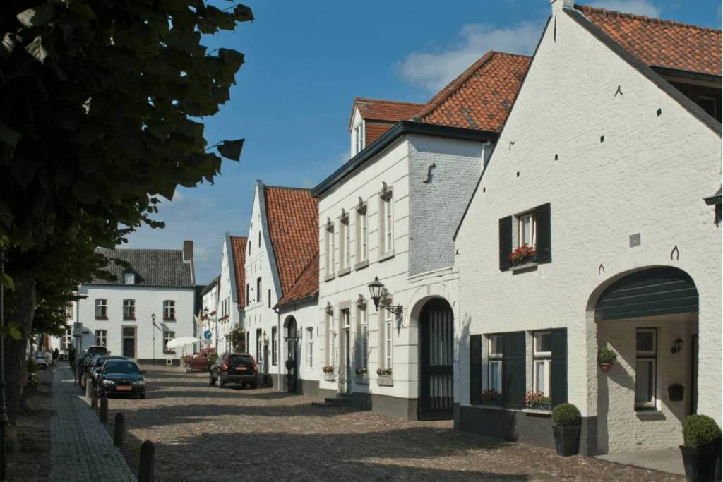 Bestrate straat in het witte stadje Thorn met historische witgekalkte huizen en rode pannendaken.