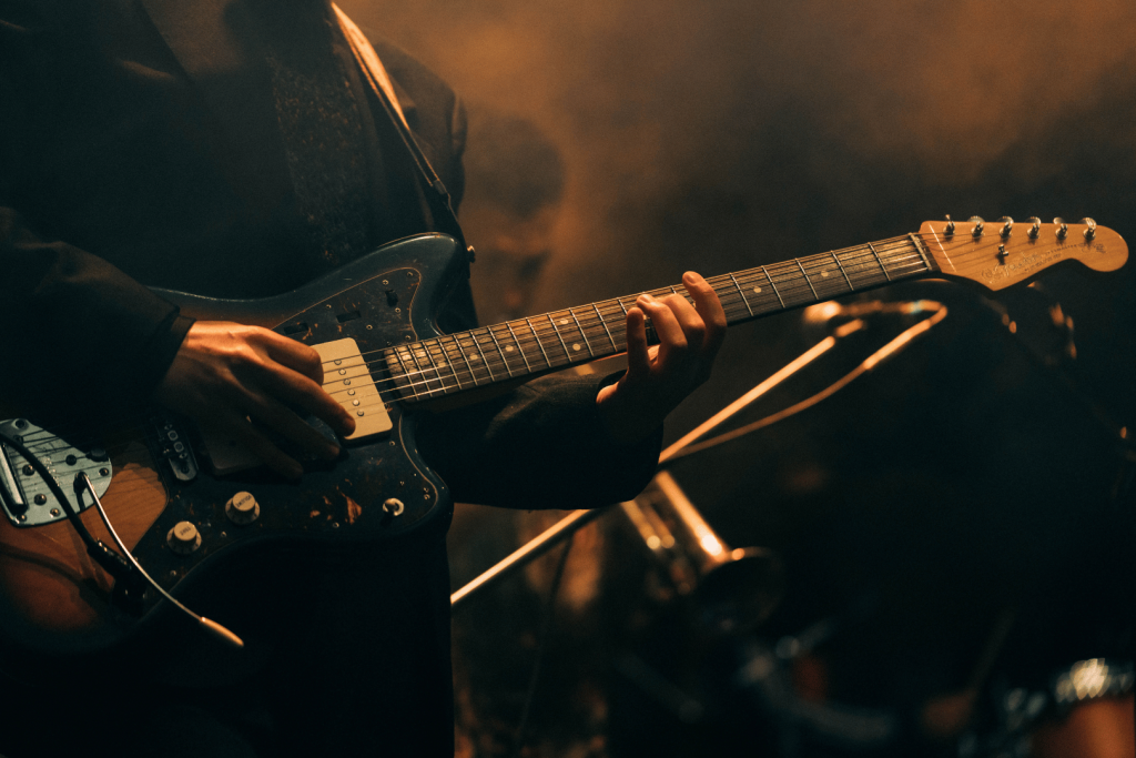 Nahaufnahme eines Musikers, der während eines stimmungsvollen Live-Jazz-Auftritts Gitarre spielt.