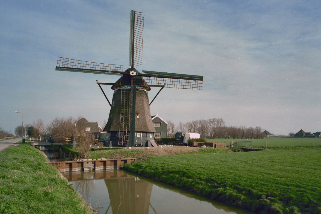 Eine historische Poldermühle am Wasser in der Polderlandschaft von De Beemster.
