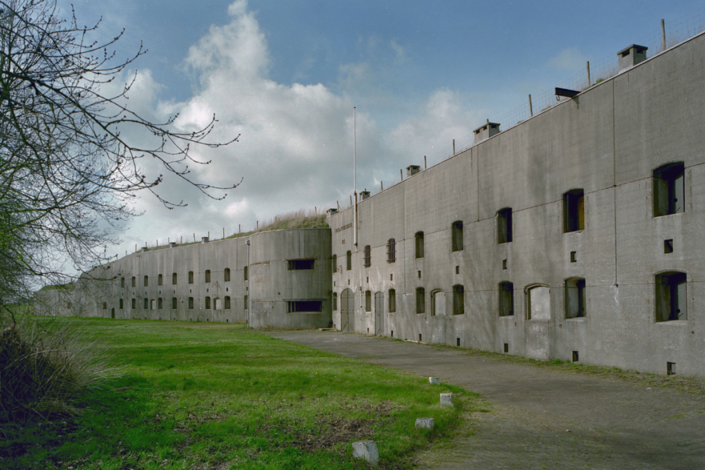 Vorderansicht der grauen Betonfassade mit zwei Stockwerken und Fenstern des Forts bei Spijkerboor.