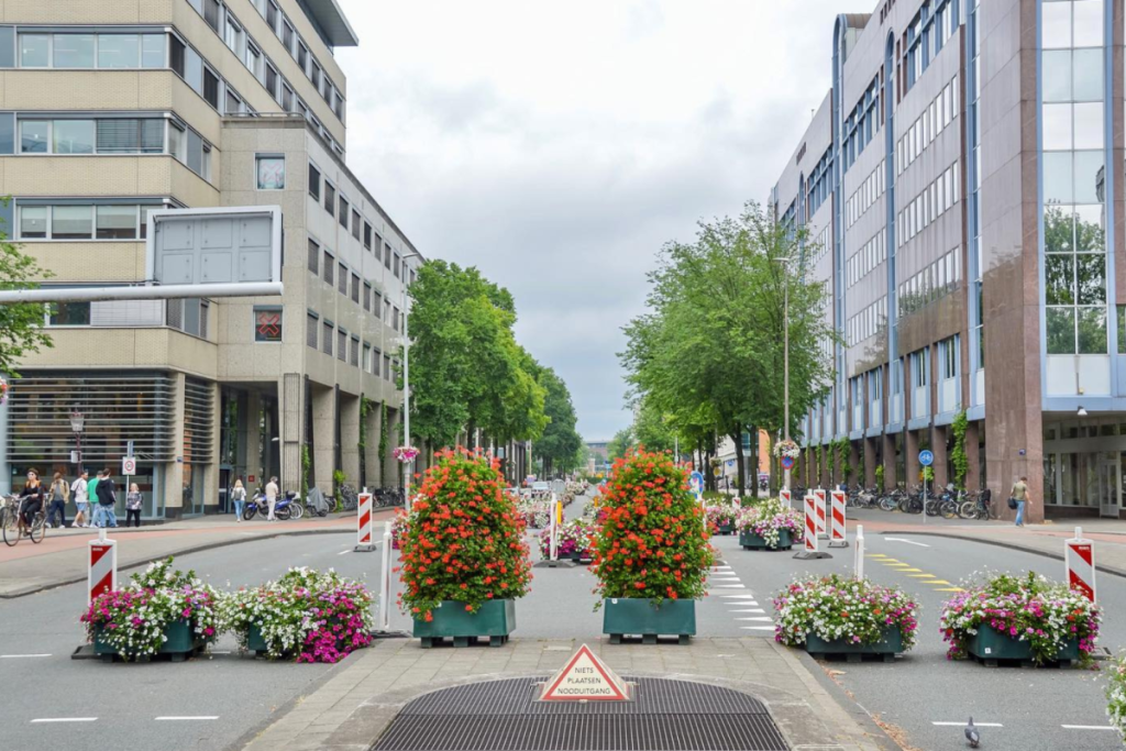 Rétrécissement de la voie de circulation sur la Weesperstraat, délimité par de grands bacs à fleurs et des poteaux de délimitation rouges et blancs