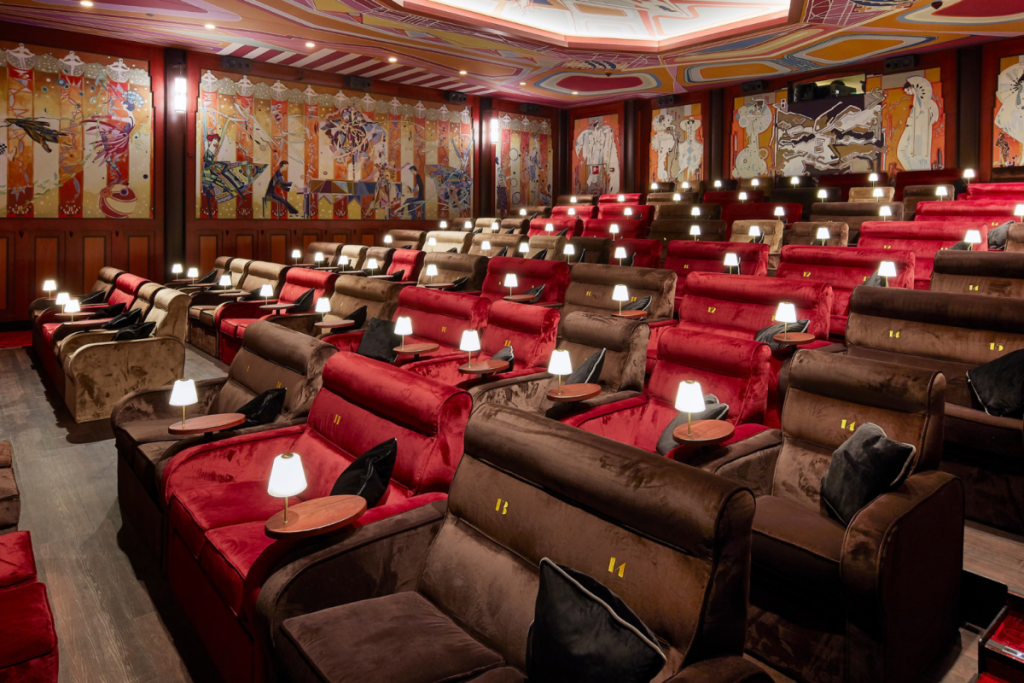Das luxuriöse Interieur des Kinosaals Tuschinski 2 in Amsterdam mit Samtsesseln, kleinen Stimmungslampen und Art-Déco-Wandmalereien.
